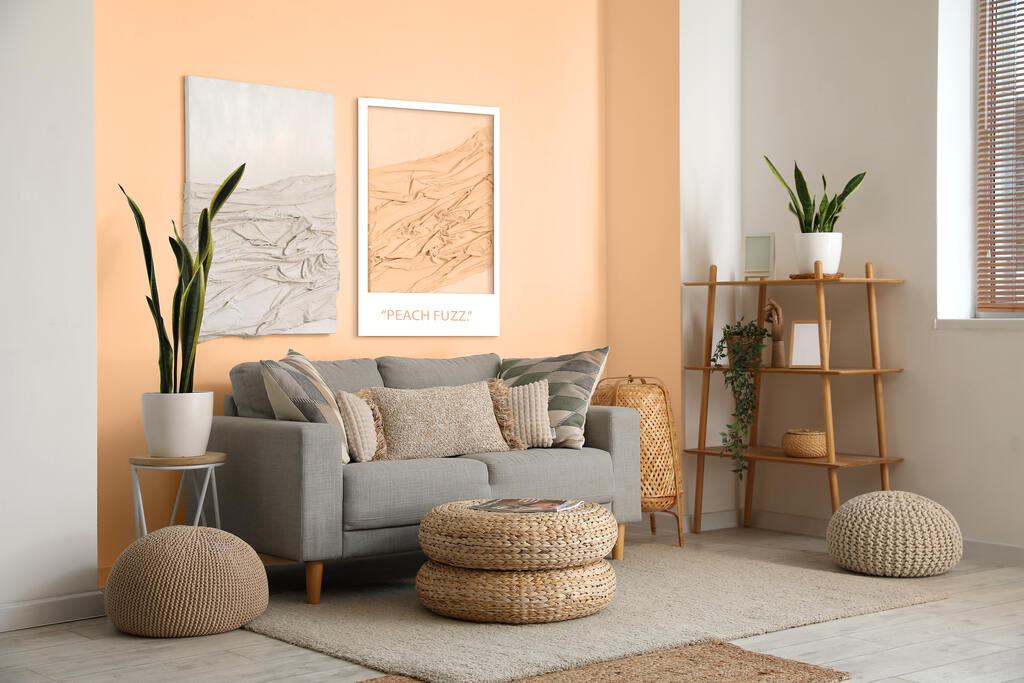 Sala de estar com parede em tom pêssego, sofá cinza claro e elementos decorativos naturais, como pufes e vasos de plantas – projeto de interiores acolhedor com toque suave.