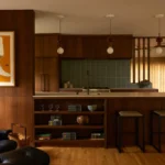Decoração de cozinha em estilo mid century modern com móveis de madeira, iluminação suspensa e detalhes art déco, criando um ambiente elegante e aconchegante.