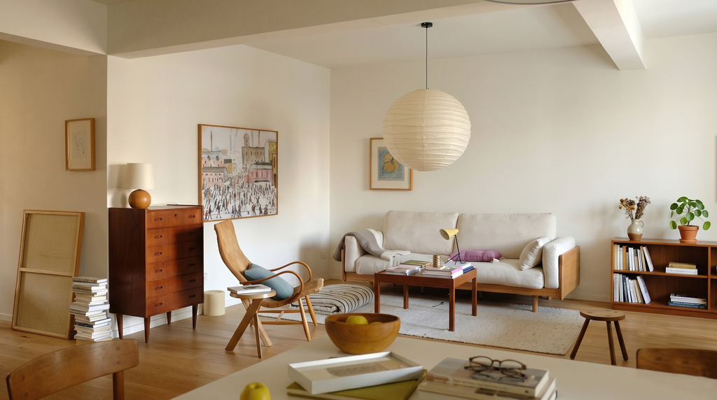 Sala de estar acolhedora em estilo escandinavo, com sofá claro, móveis de madeira natural, luminária de papel e decoração minimalista, realçando a luz e a funcionalidade.