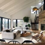 Ampla sala de estar com design de interiores em estilo escandinavo, destacando-se pela abundante luz natural, teto com vigas brancas, sofá modular claro, lareira moderna com revestimento de madeira rústica e vista panorâmica para a floresta.