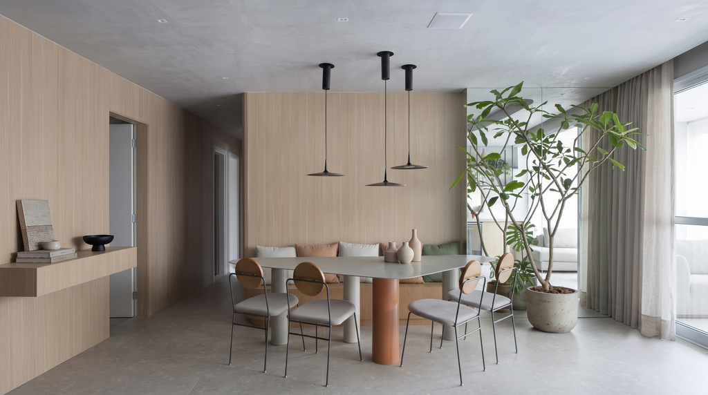 Sala de jantar elegante com mesa de design contemporâneo, cadeiras minimalistas e bancada em madeira clara, complementada por luminárias pendentes e uma grande planta, refletindo um aconchegante estilo escandinavo moderno e funcional.